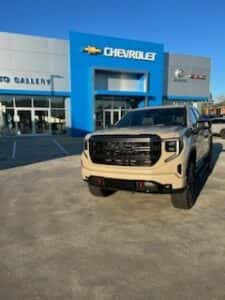 tan custom gmc pickup truck front view and dealership in backgroung