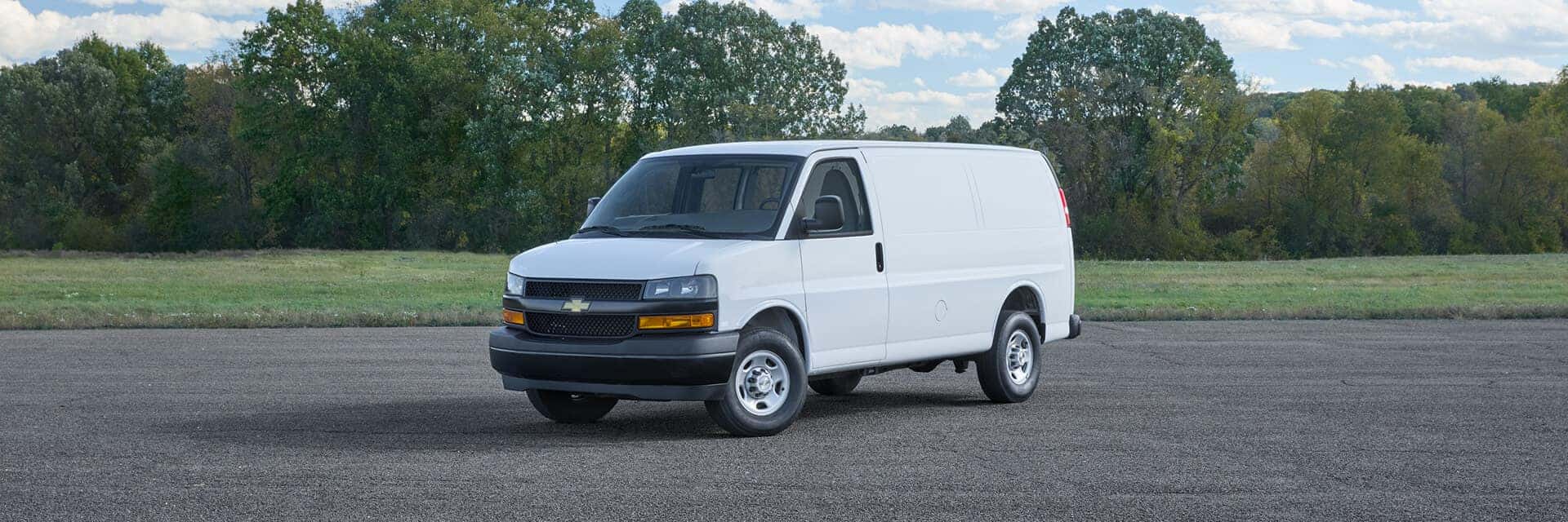 chevrolet express cargo van parked behind trees