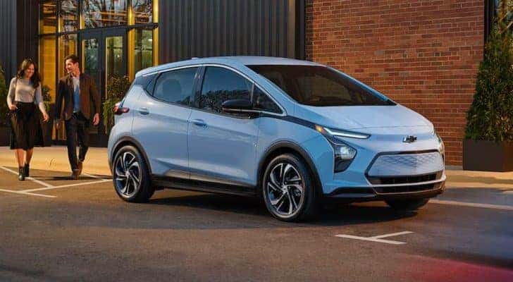 Side view of a light blue 2022 Chevy Bolt EV parked on a city street after leaving a Tennessee Chevy dealer.