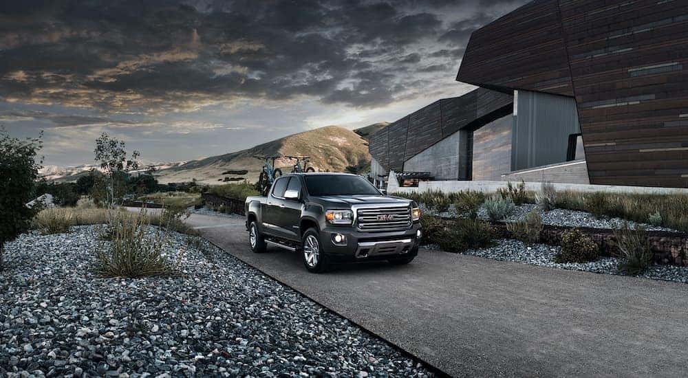 A black 2015 GMC Canyon Crew Cab SLT is shown parked on gravel after leaving a used truck dealer.