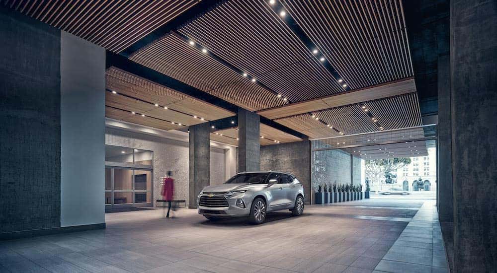 A silver 2019 Chevy Blazer Premier is shown parked in front of a hotel.