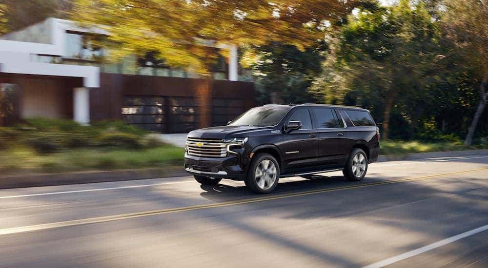 A dark blue 2022 Chevy Suburban is shown driving on a street after visiting a Selmer SUV dealer.