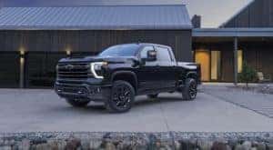 A black 2024 Chevy Silverado 2500HD High Country Midnight Edition is shown parked on a driveway.