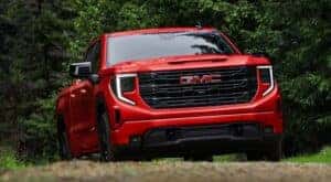 A red 2023 GMC Sierra 1500 Elevation for sale is shown from the front driving on a dirt road.