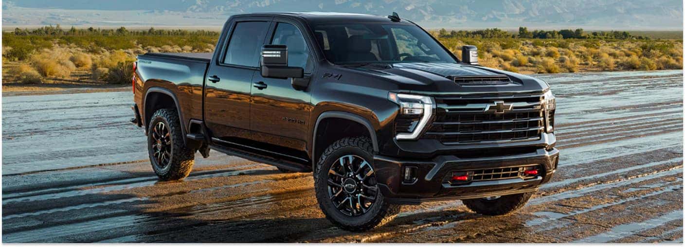 Black 2026 Chevrolet Silverado 2500 HD ZR2 pickup truck parked on wet desert terrain.
