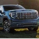 Front three-quarter view of a blue 2026 GMC Sierra 1500 Denali parked in a grassy field.