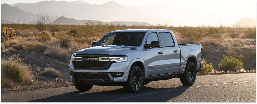 Front three-quarter view of a silver 2026 RAM 1500 pickup truck parked on a desert road.
