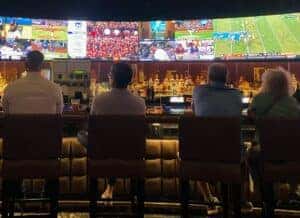 A group of people watching sports on TV at a sports bar.