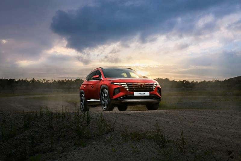 a red Hyundai SUV driving down a dirt road