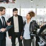 Man in Blue Business Suit Talking to Woman Touching the Car