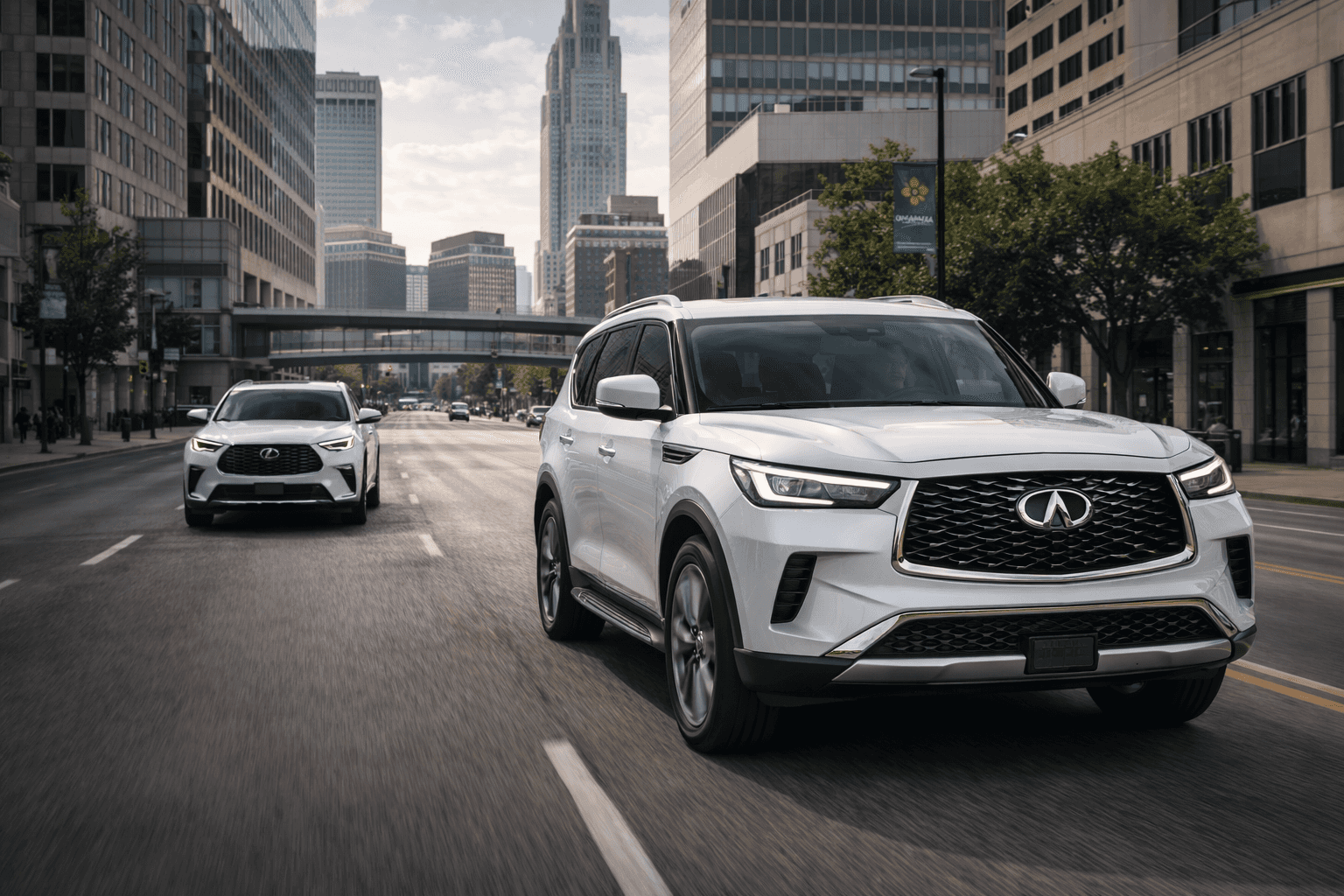 2026 INFINITI QX80 driving through downtown Omaha with a Lexus TX following behind, highlighting a luxury SUV comparison in an urban setting.