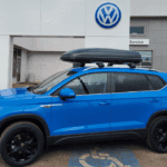 2022 Taos in blue drivers side view in front of Volkswagen dealership
