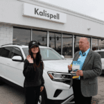 woman and man standing in front of a white Volkswagen Atlas