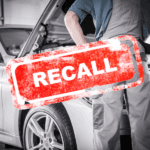 Volkswagen Technician looking under the hood of a car with a recall stamp over the picture