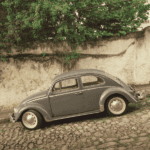 Volkswagen Beetle driving down a stone road.
