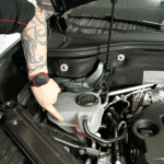 Kalispell Volkswagen Service Technician pointing to the engine coolant reservoir