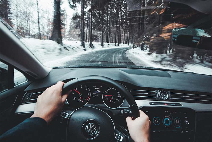 VW Steering wheel view driving Volkswagen down a snowy road