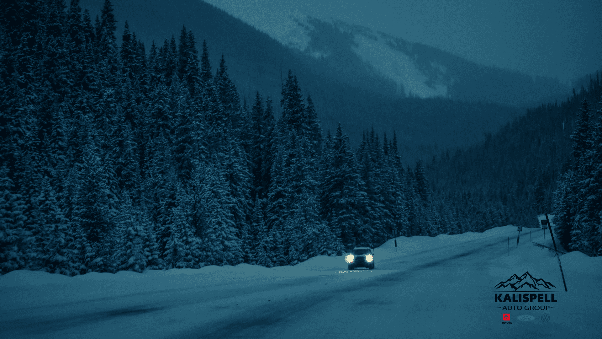 Car driving down a winter road in the mountains with snow covering the road and trees
