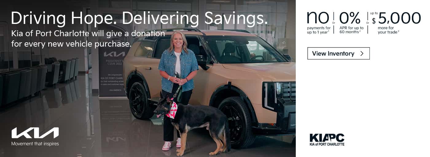 woman holding dog in fornt of car