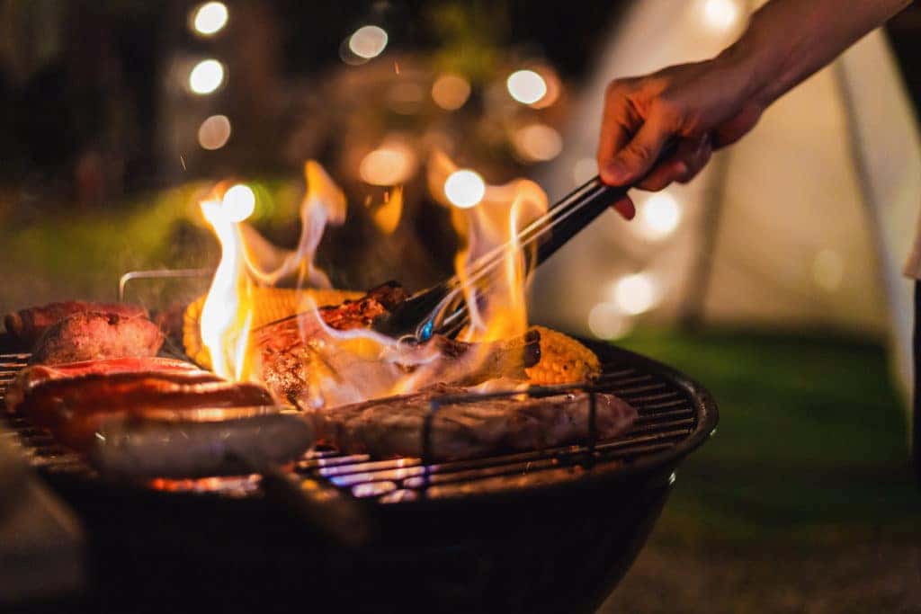 grilling with meat and flames outside at night