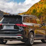 Black Mercedes-Benz GLE parked on the side of the road with a lake and mountains in the background with trees that have fall leaves