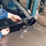 Technician is changing windscreen wipers on a car station