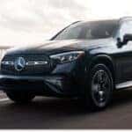 Front three-quarter view of a black 2026 Mercedes-Benz GLC SUV driving on an asphalt road.