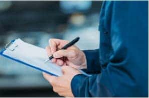 Person writing on clipboard