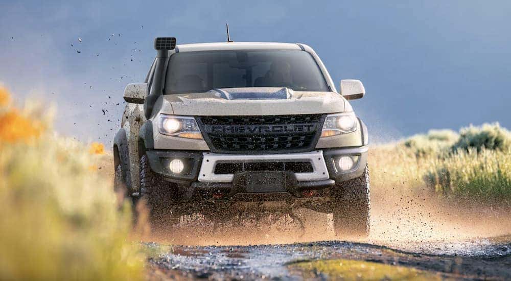 A tan 2022 Chevy Colorado ZR2 off-roading on a muddy path.