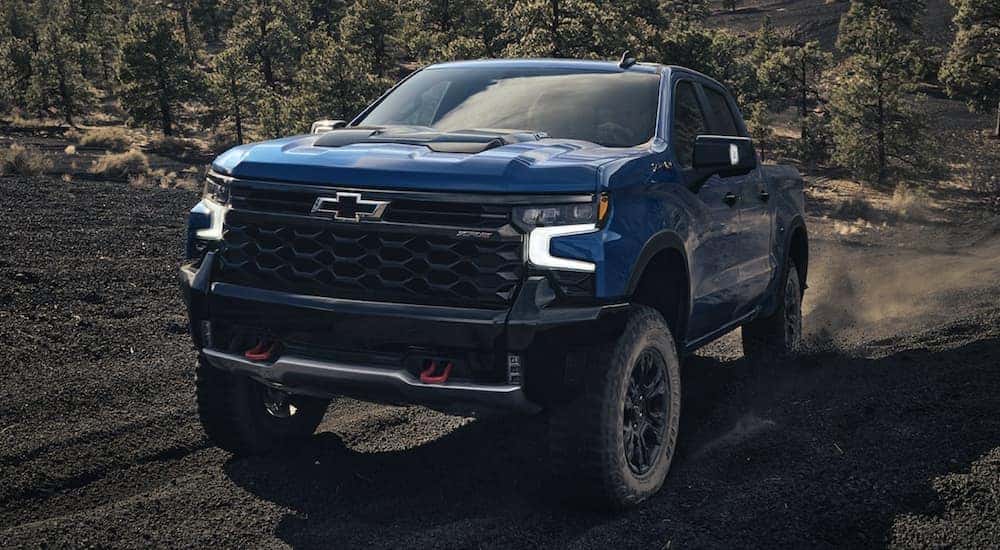 A blue 2022 Chevy Silverado 1500 ZR2 off-roading in a dirt field.