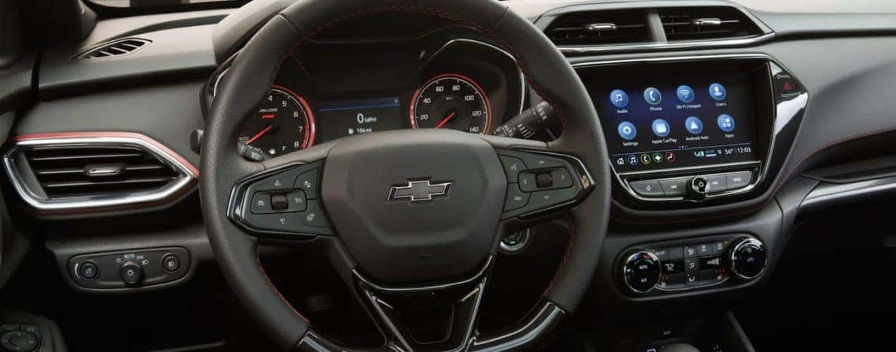 The black interior of a 2023 Chevy Trailblazer shows the steering wheel and infotainment screen.