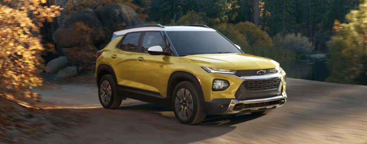 A yellow 2023 Chevy Trailblazer is shown from the front driving on a dirt road.
