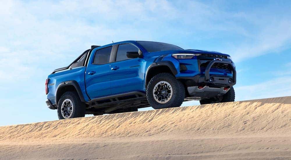 A blue 2023 Chevy Colorado ZR2 parked on the crest of a sand dune