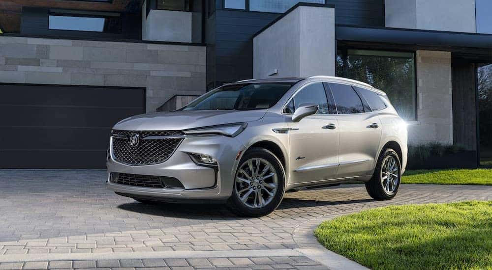 A silver 2022 Buick Enclave Avenir parked in the driveway of a modern home