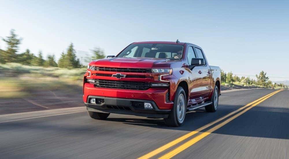 A red 2020 Chevy Silverado 1500 driving down an empty highway on a sunny day