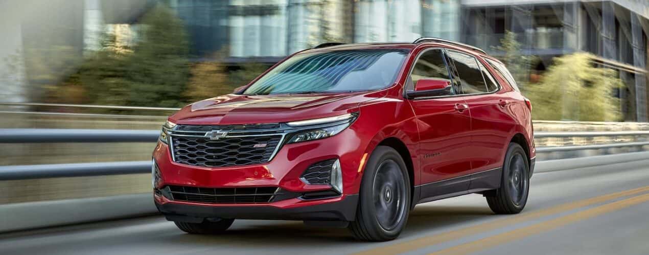 A red 2023 Chevy Equinox RS is shown driving on an open highway.