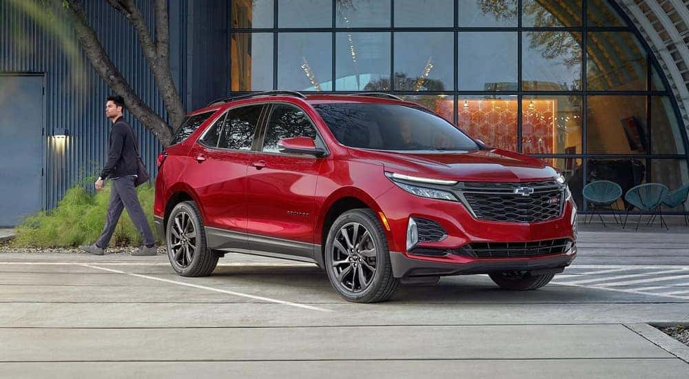 A red 2023 Chevy Equinox RS parked in front of a modern cafe with large windows