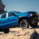 A blue 2023 Chevy Silverado 1500 ZR2 climbs up a rocky mountain trail