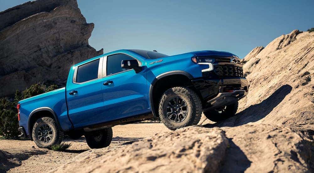 A blue 2023 Chevy Silverado 1500 ZR2 climbs up a rocky mountain trail