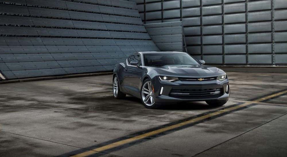 A dark gray 2016 Chevy Camaro is shown parked on the floor of a modern warehouse.