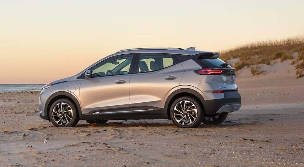 A silver 2022 Chevy Bolt EUV parked on the beach at sunrise