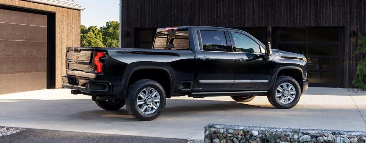 A black 2024 Chevy Silverado 2500 HD High Country is shown from the side parked in a driveway.