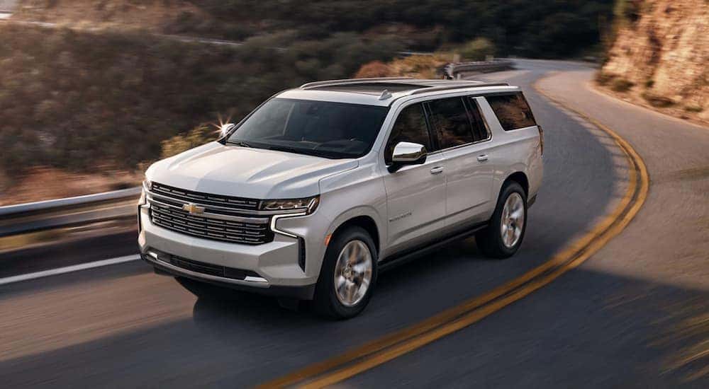 A white 2023 Chevy Suburban driving on a windy mountain road