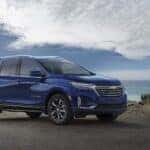 A blue 2023 Chevy Equinox Premier parked at a rocky ocean shoreline