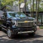 A black 2024 Chevy Silverado 2500 HD High Country parked outside a modern home in the forest