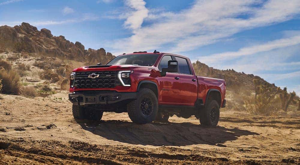A red 2024 Chevy Silverado 2500 HD ZR2 Bison off-roading through a sandy desert area