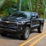 A black 2023 Chevy Colorado is shown driving on a bridge after visiting a Chevy truck dealer near Franklin.