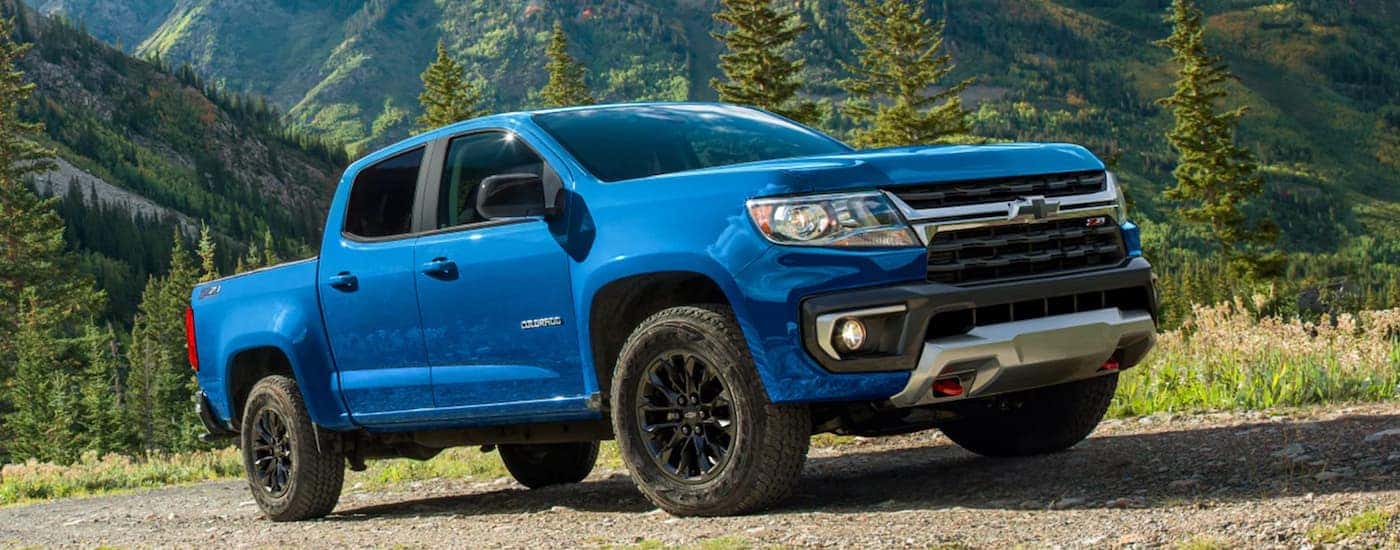 A blue 2022 Chevy Colorado Z71 is shown parked on a dirt road on a mountain trail.