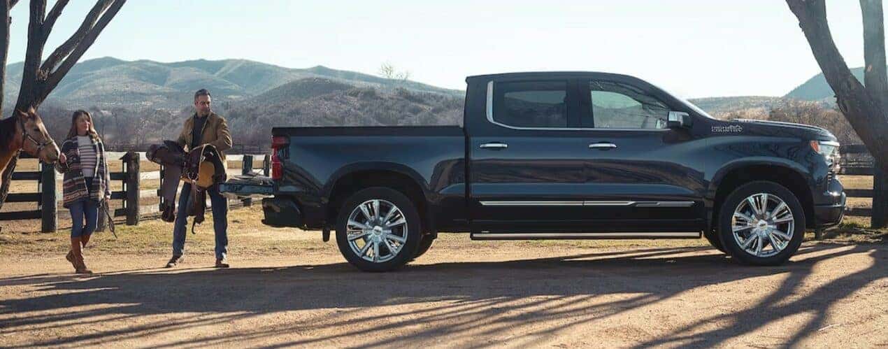 After participating in a 2024 Chevy Silverado 1500 vs 2024 Ford F-150 comparison, a black 2024 Chevy Silverado 1500 High Country, is shown parked on a ranch.