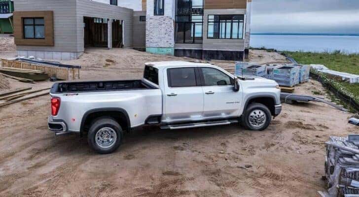 A popular Chevy Silverado for sale, a white 2024 Chevy Silverado 3500 HD High Country, is shown parked near a build site.